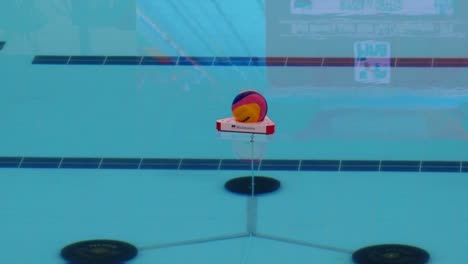 Zoom-water-polo-swimoff-Malmsten-Flotation-Rig-players-dispute-begining-of-play-at-referee's-whistle-both-teams-swim-to-midpoint-of-the-pool-Mikasa-ball-in-a-floating-ring