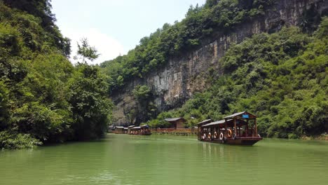 Zhangjiajie,-China---August-2019:-Traditionelle-Holzboote,-Die-Auf-Den-Wassern-Eines-Kleinen-Schmalen-Sees-Zwischen-Hohen-Und-Hohen-Felsklippen-Des-Majestätischen-Grand-Canyon-Im-Zhangjiajie-nationalpark-Segeln