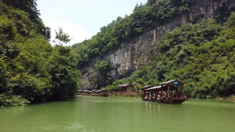 Zhangjiajie,-China---Agosto-De-2019:-Barcos-De-Madera-Tradicionales-Que-Navegan-En-Las-Aguas-De-Un-Pequeño-Lago-Estrecho-Entre-Acantilados-Rocosos-Altos-Y-Altos-Del-Majestuoso-Gran-Cañón-En-El-Parque-Nacional-De-Zhangjiajie