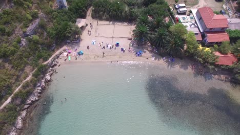 Aerial-view-of-a-warm-clear-lagoon-and-beach-filled-with-people-sunbathing-and-swimming