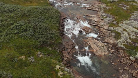 Glacial-meltwater-river-flowing-in-Norway-Hardangervidda-landscape,-aerial-view