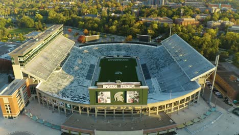 Aerial-flyover,-empty-American-gridiron-football-stadium-in-early-morning