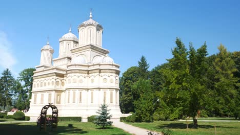 Panning-shot-of-the-Curtea-de-Arges-monastery,-Romania,-and-his-gardens-on-a-sunny-and-warm-summer-day