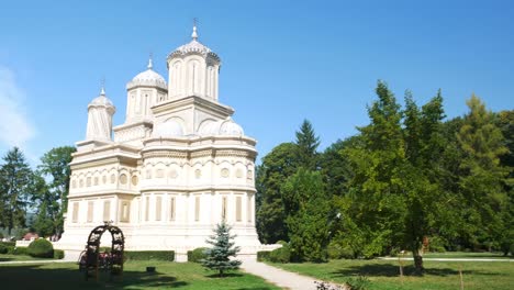 Toma-Panorámica-Del-Monasterio-De-Curtea-De-Arges,-Rumania,-Y-Sus-Jardines-En-Un-Soleado-Y-Cálido-Día-De-Verano