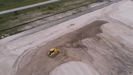 Overheard-view-of-yellow-tractor-at-a-construction-site,-aerial-drone-shot