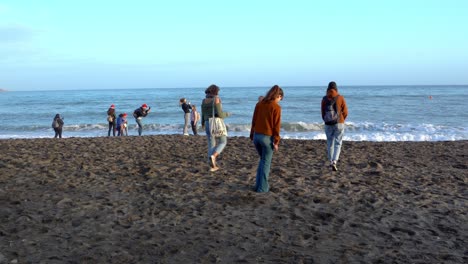 Female-tourists-walk-towards-sea-Malagueta-beach,-Malaga,-Spain