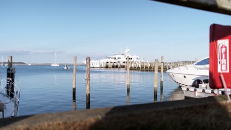 Handheld-Aufnahme-Durch-Einen-Wachzaun-Einer-Luxusjacht,-Die-Im-Jachthafen-Von-Sag-Harbour-Vor-Anker-Liegt