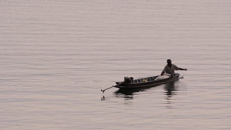 Fisherman-silhouetting-as-he-is-casting-and-drawing-his-net-in-the-River-before-dark,-in-slow-motion