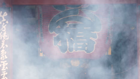 Giant-red-paper-lantern-partially-hidden-by-incense-smoke-in-Senso-ji-Temple,-Tokyo