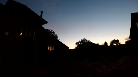 Night-lapse-of-a-Kentish-barn,-lifestyle-shot-with-view-of-the-TV-through-the-cosy-homes-window-at-sunset