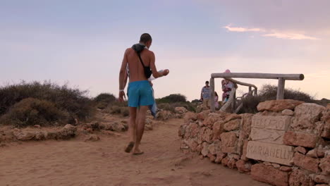 Visitors-Making-Their-To-Beach-At-Vendicari-Reserve-With-Dramatic-Pink-Blue-Skies-In-Background,-Italy