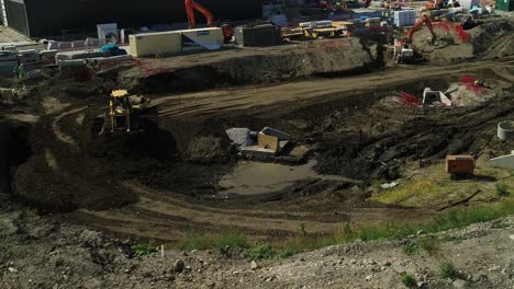 Wide-aerial-view-of-a-bulldozer-moving-earth-on-a-construction-site-in-the-UK