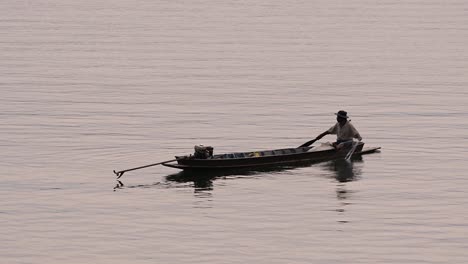 Pescador-Perfilando-Mientras-Lanza-Y-Saca-Su-Red-En-El-Río-Antes-Del-Anochecer,-En-Cámara-Lenta