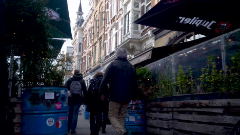 Cinco-Personas-Caminando-Por-Cafeterías-Y-Tiendas-Nieuwe-Binnenweg,-Rotterdam,-Países-Bajos,-Con-Plantas-Que-Crecen-A-Partir-De-Contenedores-De-Basura