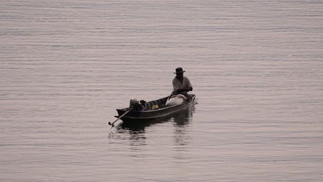 Fisherman-silhouetting-as-he-is-casting-and-drawing-his-net-in-the-River-before-dark,-in-slow-motion