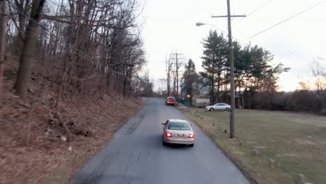 Aerial-tracking-shot-of-brown-car-going-up-hill-during-winter