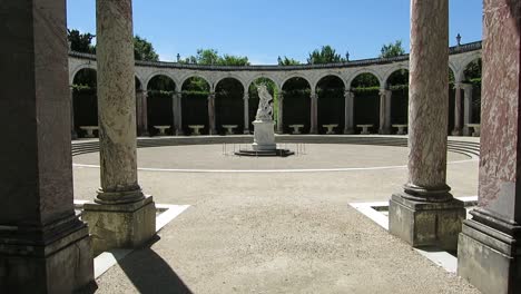 View-of-a-marble-statue-on-the-center-of-a-small-arena-in-the-Versailles-Palace-gardens,-Paris,-France