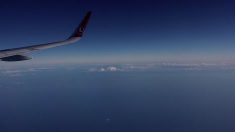 Fensteransicht-Des-Flügels-Eines-Flugzeugs,-Das-In-Den-Himmel-Fliegt,-Mit-Klarem-Und-Blauem-Horizont,-Der-Nach-Baku-Aserbaidschan-Reist