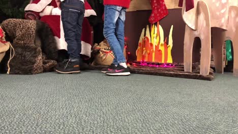 Time-lapse-footage-of-school-children-coming-to-visit-Santa-Claus-in-his-grotto-before-Christmas,-speaking-to-him-about-whether-they-have-been-good-children,-and-then-getting-a-present-each
