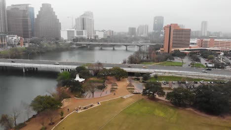 A-drone-flies-backward-capturing-images-of-lamar-beach-metro-park-at-ladybird-lake-and-the-colorado-river-in-downtown-austin-on-a-foggy-day