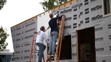 Dos-Hombres-Trabajadores-De-La-Construcción-Construyendo-Una-Pequeña-Casa-Para-Una-Vida-Alternativa