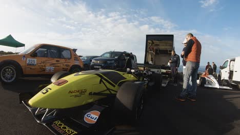 Dos-Hombres-Hablando-Sobre-El-Coche-De-Carreras-Amarillo-Estacionado-Al-Lado-De-La-Carretera-En-La-Colina-En-Imtahleb-Malta-En-Un-Día-Soleado---Primer-Tiro-Gopro