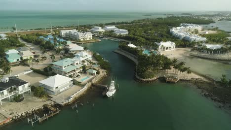 Luftaufnahme-Des-Resorts-Und-Der-Nachbarschaft-Auf-Knight&#39;s-Key-Im-Marathon-Florida-Mit-Fischerboot-Und-Palmen,-Die-In-Wind-Und-Ozean-Wehen,-Im-Hintergrund-Nach-Vorne-Schwenken
