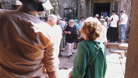 Toma-Cercana-Del-Guía-Turístico-Hablando-Y-La-Madre-Turista-Camina-Alegremente-Hacia-La-Hija-Turista-Mientras-Otros-Turistas-Caminan-Fuera-De-La-Entrada-De-Un-Templo-Cerca-De-Angkor-Wat