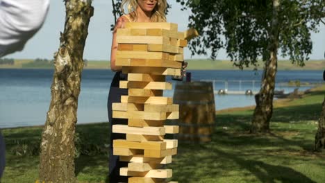 Woman-plays-Large-Outdoor-Game-Of-Jenga,-SLOW-MOTION