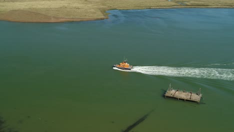 Toma-Aérea-De-La-Tripulación-De-Un-Bote-Salvavidas-Rnli-Navegando-A-Lo-Largo-De-Un-Cuerpo-De-Agua-Abierto