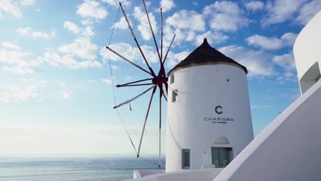 Molino-De-Viento-Blanco-Con-Vistas-Al-Océano-Con-El-Cielo-Azul-De-Fondo,-Santorini,-Grecia