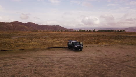 Parked-Suv-at-the-barren-upland-game-hunting-area-California,-drone-shot