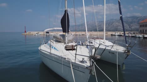 Zwei-Weiße-Segelboote-Schaukeln-Sanft,-Während-Sie-In-Einem-Ruhigen-Kroatischen-Jachthafen-Festgemacht-Sind