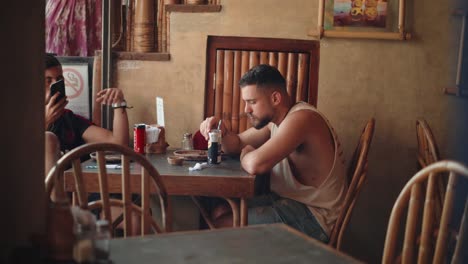 El-Nido,-Philippines---Two-Male-Foreign-Tourists-Drinking-Cold-Beverage-In-Can-While-Talking-In-A-Restaurant-In-Palawan---Close-up-Shot