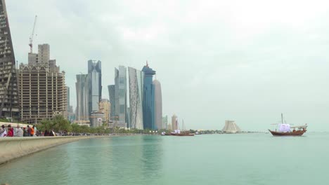 Timelapse-De-La-Vista-Del-Horizonte-De-Doha-Con-Grandes-Banderas-Y-Barcos-Tradicionales-Y-Retrato-Tamin-En-Barcos