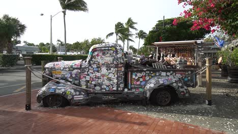 Old-Truck-With-Stickers-All-Over-on-Display-With-Palm-Trees-in-Background-in-key-West,-Florida