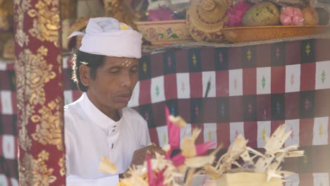 Hindu-priester,-Der-An-Einem-Bunt-Geschmückten-Altar-Mit-Blumenopfer-Betet,-Schnippt-Ein-Blütenblatt-Weg,-Wenn-Das-Gebet-Beendet-Ist