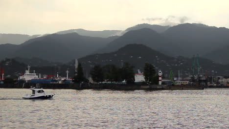 A-small-yacht-heading-out-to-the-open-seas-from-an-industrial-harbor