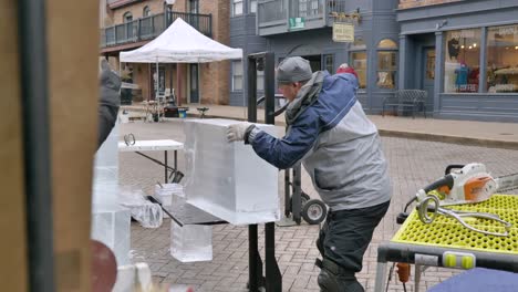 Toma-En-Cámara-Lenta-Del-Escultor-De-Hielo-Levantando-Un-Bloque-De-Hielo-En-Una-Plataforma-Rodante