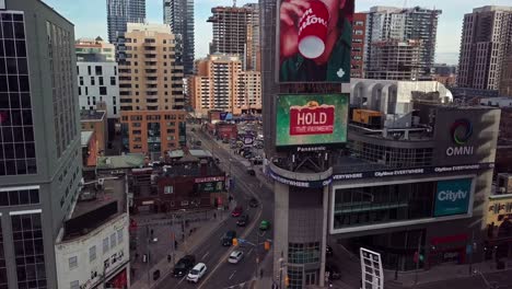 Aerial-View-of-Tall-Condo-Buildings-and-Ads-in-Downtown-City,-Wide-Dolly-In-near-Sunset