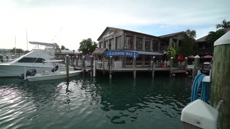 Wide-shot-of-Wooden-Marina-With-Boats-Docked-in-Water-and-Pillars-in-Foreground-Tracking-Forward