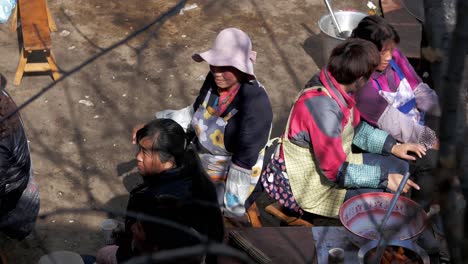 Multi-ethnic-Chinese-wedding-in-Weixi,-Yunnan,-People-sitting-preparing-to-eat-rice-bowls---vegetable-healthy-meals