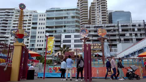 Luna-Amusement-Park-Ranger-and-Pirate's-Revenge-rides-with-people-admiring-the-place,-northern-shore-on-a-cloudy-day,-Pan-right-reveal-shot