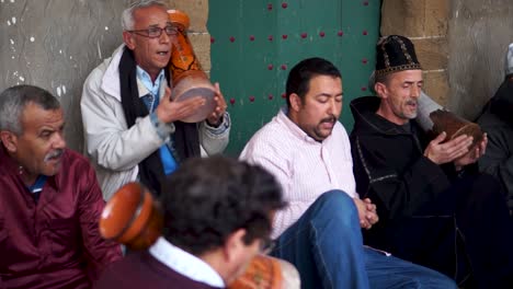 Cámara-Panorámica-De-Derecha-A-Izquierda-Que-Muestra-Una-Reunión-De-Hombres-Vestidos-Con-Ropa-Tradicional-Cantando-Y-Golpeando-Tambores-Entrando-En-Trance-Durante-Una-Ceremonia-Sufí