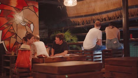 El-Nido,-Philippines---Foreign-Tourists-Talking-While-Waiting-For-Their-Food-In-A-Native-Restaurant-At-Night---Closeup-Shot