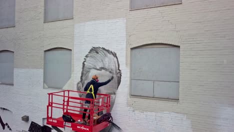 Graffiti-Painter-Creating-Portrait-on-Wall-of-Building,-Drone-Pedestal