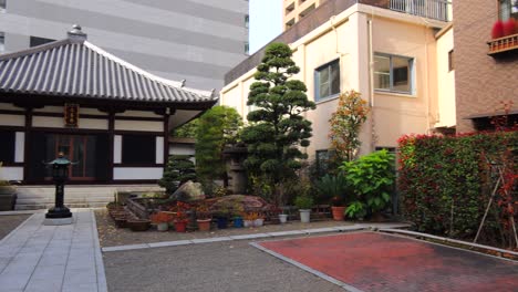 Cute-Japanese-traditional-house-with-trees-and-cars-around-in-Tokyo,-4K-panning-left