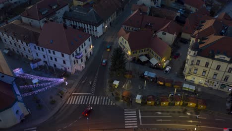 Christmas-lights-switch-on-in-main-square-of-small-town,-aerial-time-lapse-of-market-with-decoration,-slow-zoom-out