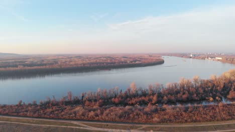 An-Aerial-Drone-Shot-Moving-Out-Over-the-Danube-River-in-Eastern-Europe-with-Clear-Bright-Blue-Skies-in-the-Evening-as-the-Sun-Sets