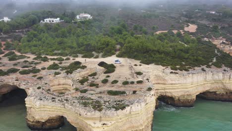 Strand-Von-Fontainhas-In-Südportugal-Mit-Campingwagen,-Der-Auf-Erodierten-Meereshöhlen-Geparkt-Ist,-Luftwagen-Aus-Der-Luft